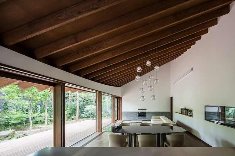 The main space is a living and dining one, with an attic roof accented with pendant glass bubble lamps and cool forest views