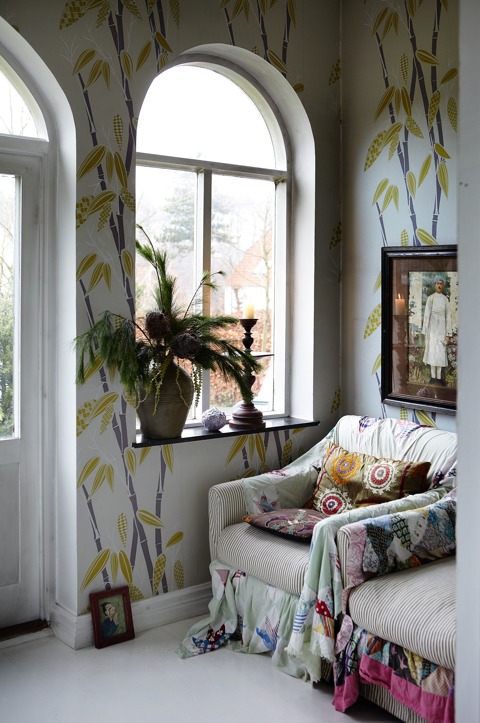 This colorful nook features a candle in a vintage candle holder and some evergreens with piinecones on the windowsill This colorful nook features a candle in a vintage candle holder and some evergreens with piinecones on the windowsill
