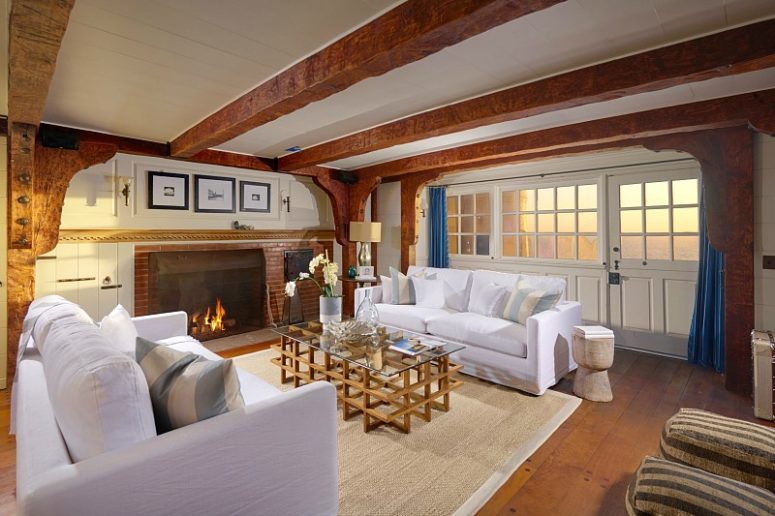 This living room features dark wooden beams, a duo of white sofas and a jute rug