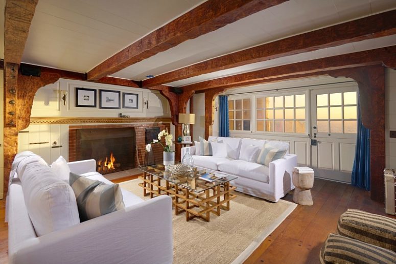 living room with gorgeous beams on a ceiling This living room features dark wooden beams, a duo of white sofas and a jute rug