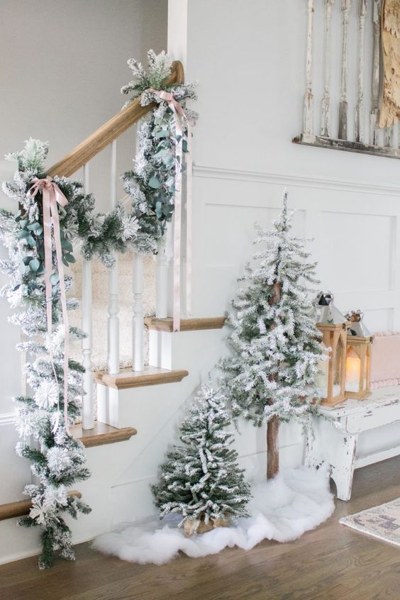 a flocked evergreen garland with bows and a duo of flocked Christmas trees for a winter wonderland touch