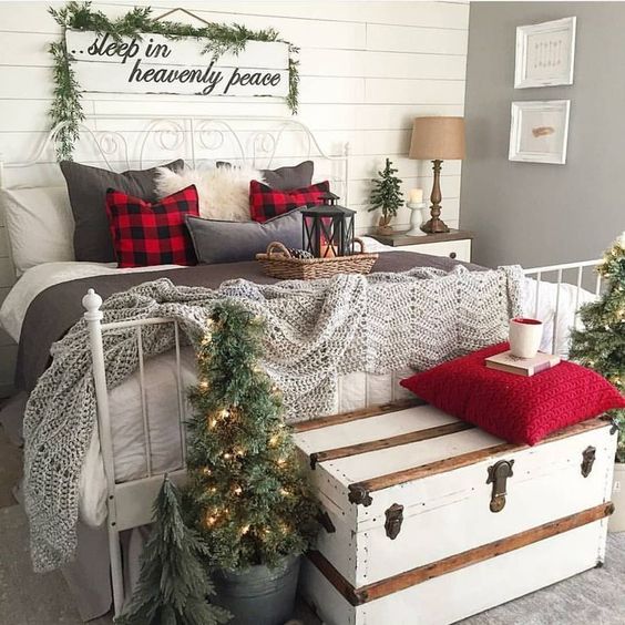 a vintage farmhouse Christmas bedroom with plaid pillows, fur, Christmas trees and a sign over the bed