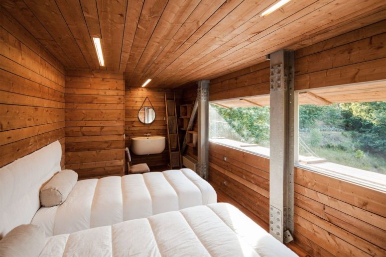 The guest bedroom is shared, there's also a mudroom right here, the space is clad with wood and there are metal pillars