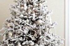 10 a snowy Christmas tree with pearly and silver ornaments, snowy branches and a silver topper