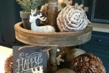 11 a holiday stand with deer figurines, pinecones, ornaments, a sign and fake evergreens
