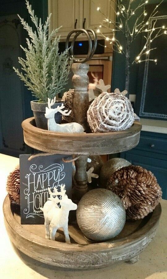 a holiday stand with deer figurines, pinecones, ornaments, a sign and fake evergreens