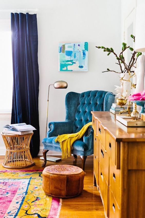 a yellow wooden sideboard and a turquoise upholstered chair look very harmonious together