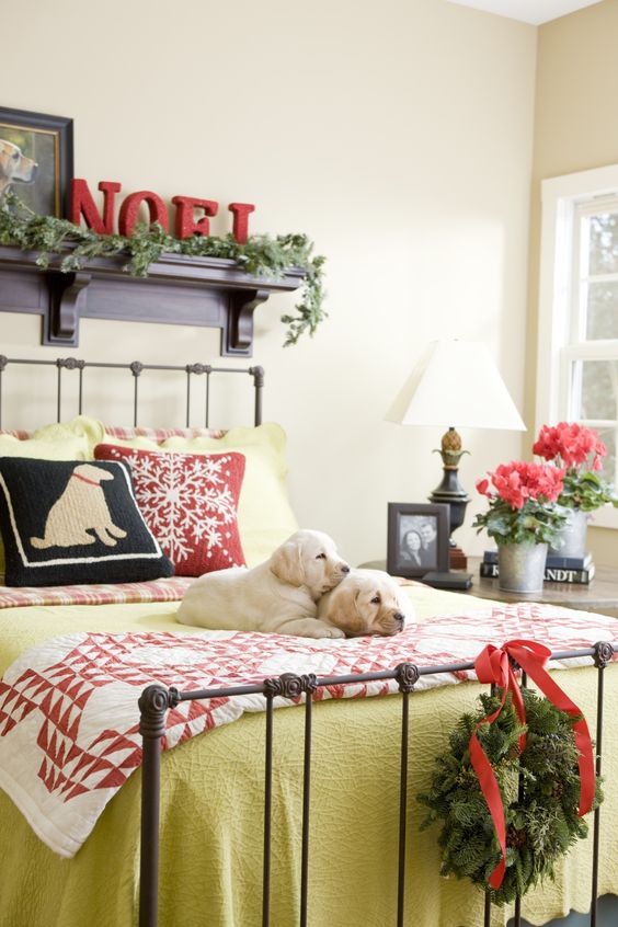 a colorful sleeping space with mustard and plaid bedding, an evergreen garland and wreath, red blooms