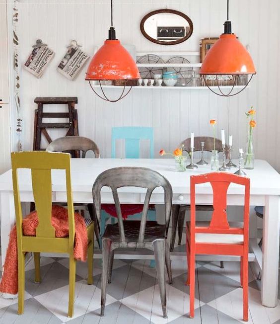 an orange chair matches the pendant lamps and some throws on the chairs to make the space harmonious