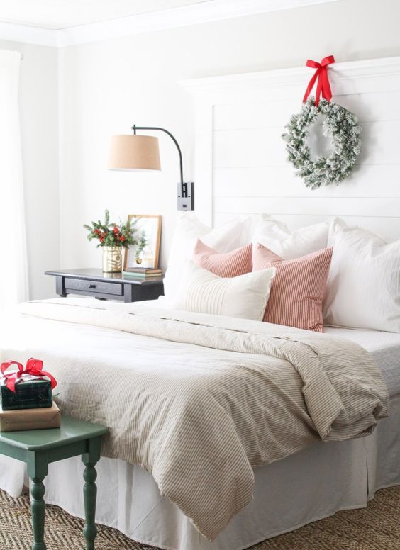 a beautiful Christmas bedroom with snowy wreaths, a bench with gifts, striped bedding and branches