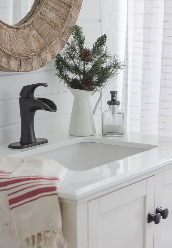 a simple evergreen arrangement with pinecones in a white pitcher is enough to make your space festive