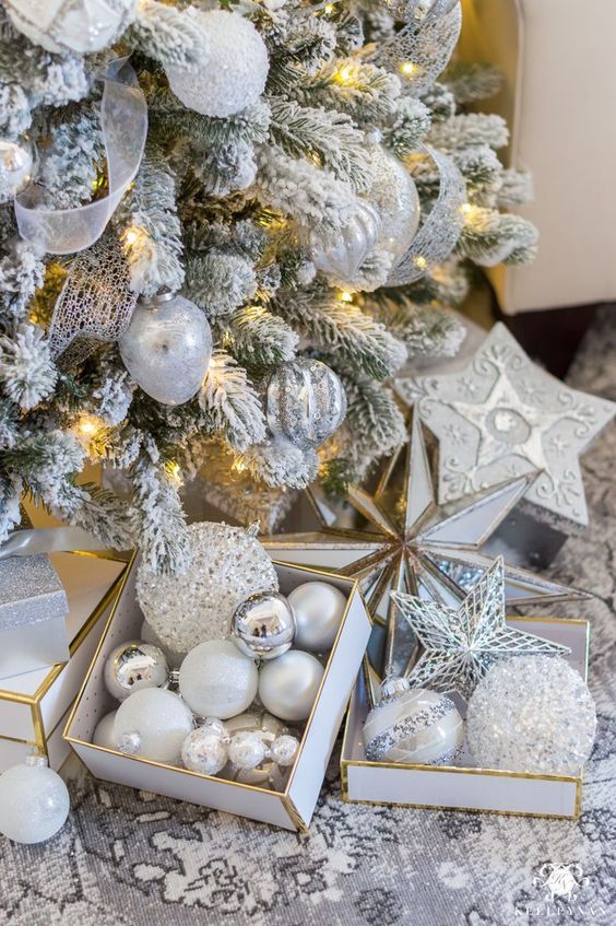 a snowy Christmas tree with snowy, silver and silver glitter ornaments plus lights creates a winter wonderland
