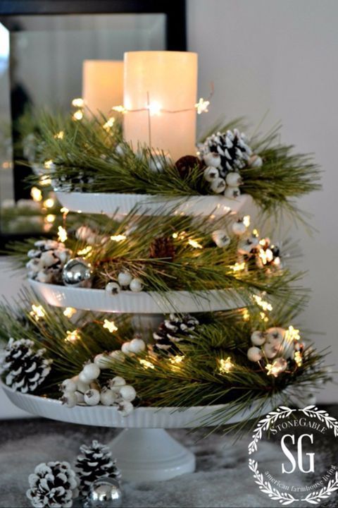 a stylish cupcake stand with evergreens, star lights, fake berries, snowy pinecones and candles