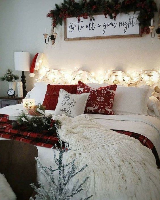 create a welcoming space with lights, printed and knit pillows, a white blanket, a sign over the bed decorated with pinecones and evergreens