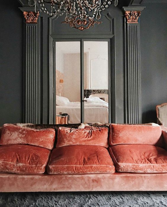 a luxurious coral velvet sofa with cushions adds color to the muted grey space