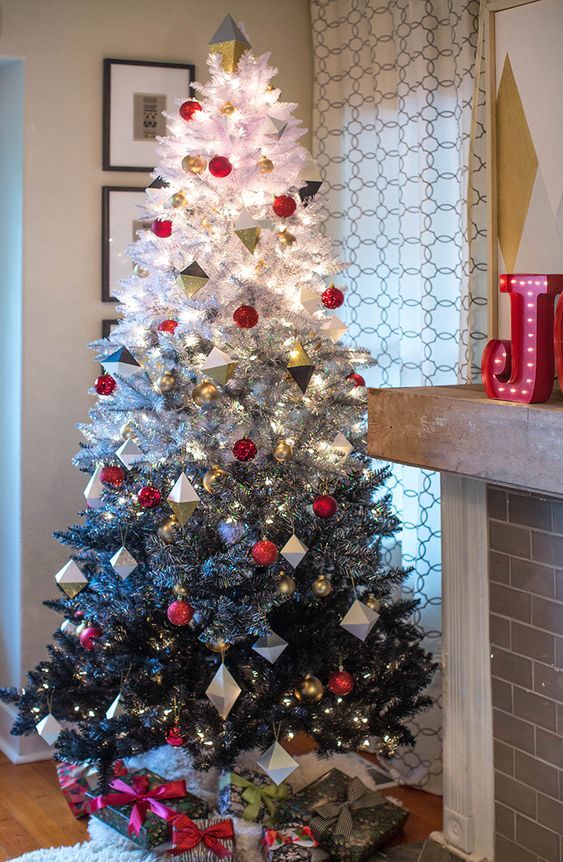 a cool modern Christmas tree with an ombre effect from white to silver and black decorated with red baubles adn metallic geometric ornaments