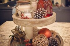 19 a two-tiered Christmas tray with fake berries, pinecones, a twine ball and beautiful candles