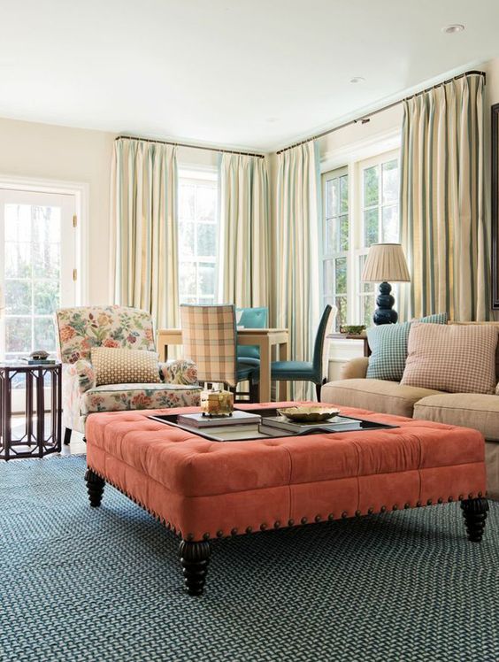 a large coral upholstered ottoman makes a colorful statement in this neutral living room