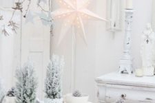 21 a white Christmas tablescape with snowy potted trees, stars around and whitewashed pinecones in bowls