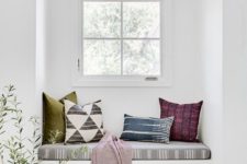 21 a white space with colorful textiles with prints that make this windowsill bench brighter and catchier