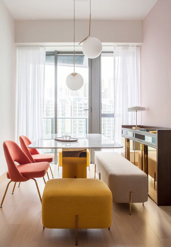 a duo of coral chairs, a yellow upholstered stool and a neutral upholstered bench make the space catchy a duo of coral chairs, a yellow upholstered stool and a neutral upholstered bench make the space catchy