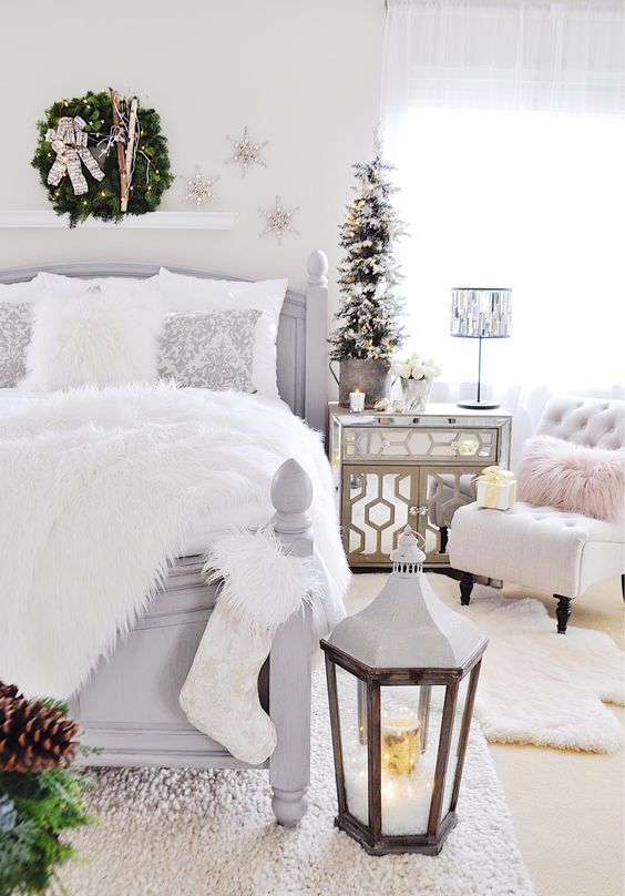 a welcoming Christmas bedroom with faux fur, an oversized lantern with lights, a flocked Christmas tree, silver snowflakes and a wreath with skis
