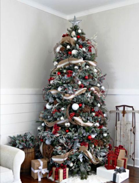 a rustic snowy Christmas tree done with white, silver and red ornaments, branches and striped burlap ribbon