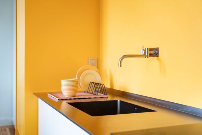 yellow kitchen design The warm yellow tone of the walls is reflected into the kitchen counter, adding a comfortable vibe to the decor