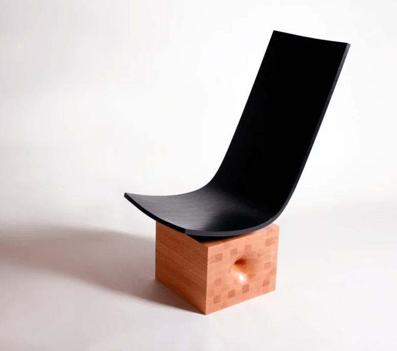This lounge chair is placed on a large cube with a wormhole and a has a comfy black lounger