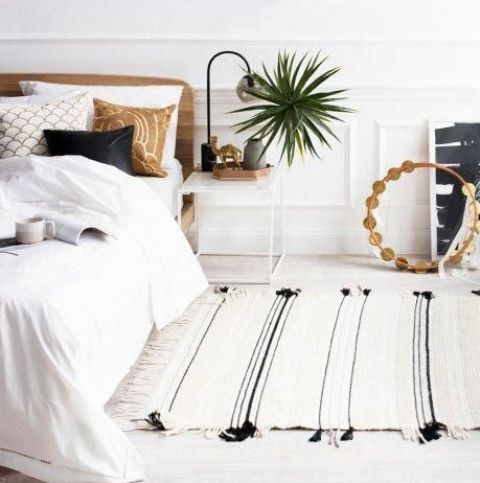 a welcoming and relaxed bedroom with layered neutrals and touches of black for some drama and depth