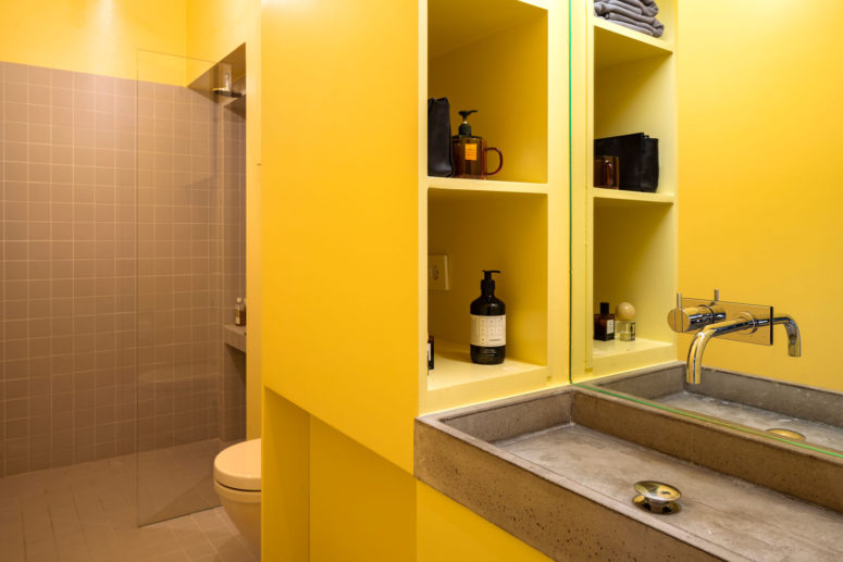 yellow bathroom design The bathroom combines yellow and greys - grey tiles and a concrete sink