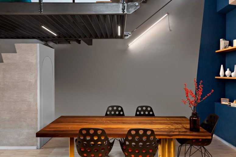 a dining space that features an interesting geometric decor The dining space features geometric decor, industrial lighting, a bold dining table and metal perforated chairs