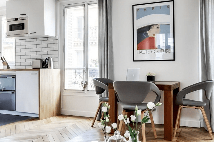 The dining space is placed between the windows and is styled with comfy grey chairs and a vintage poster The dining space is placed between the windows and is styled with comfy grey chairs and a vintage poster