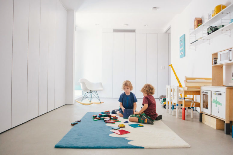 The kids' room is done with hidden storage inside white cabients and there's some comfy kids' furniture and bright touches