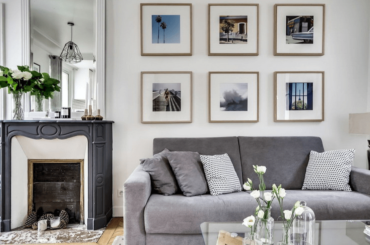 minimalist gallery wall in a living room The living room is done with comfy grey furniture, a stylish gallery wall and a chic fireplace with pinecones inside