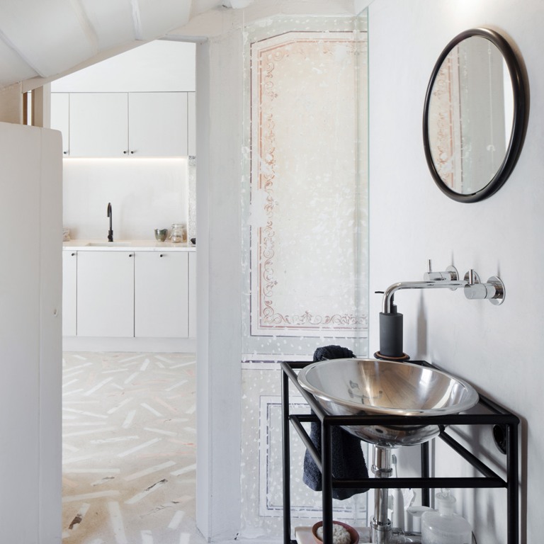 The original frescoes and wall coverings contrast the modern vanity and sink creating a unique space