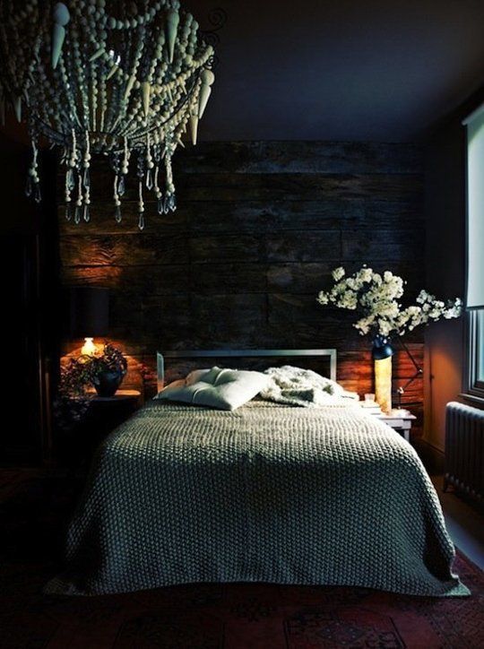 a moody bedroom with a weathered wooden wall and a boho bead chandelier is very welcoming