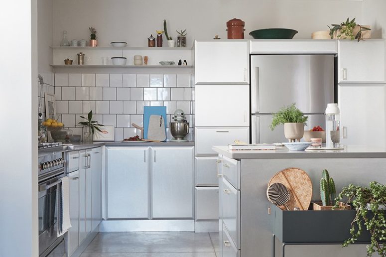 The kitchen is white and shiny, a white tile backsplash is accented with black grout