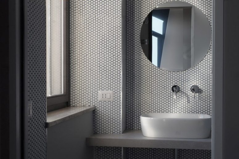 contemporary bathroom design with cool penny tiles The bathroom is clad with white penny tiles, there's an oval sink and a round mirror