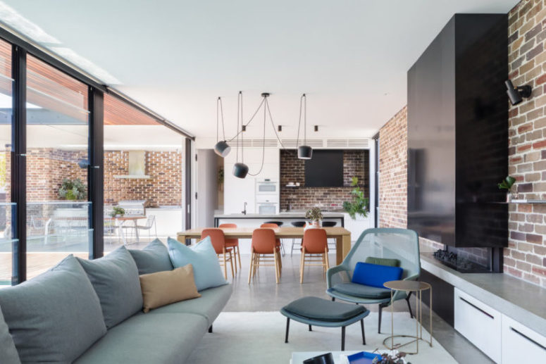 The dining space with chaotically suspended lamps over it separates the kitchen from the living room
