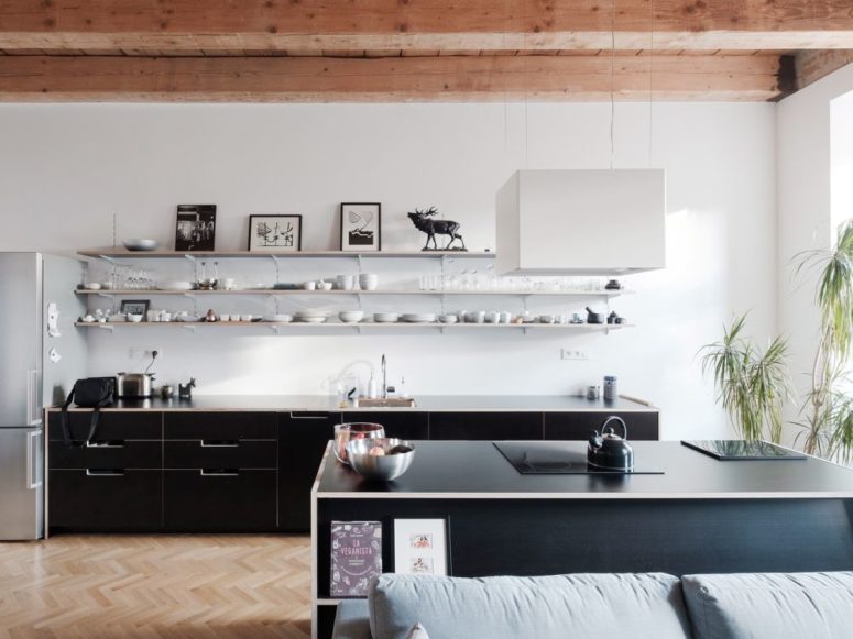 The kitchen is done with black sleek cabinets and a white vent for a contrasting look