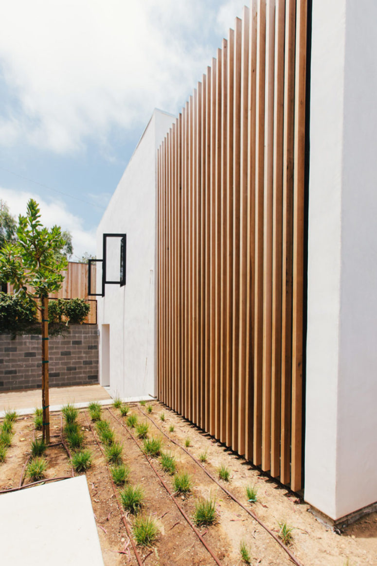 Outside the house is done in white and clad with wood, there's minimalist landscaping