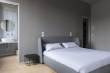 07 The bedroom is done in the shades of grey, with grey walls and a grey upholstered bed and a duo of metal bedside tables
