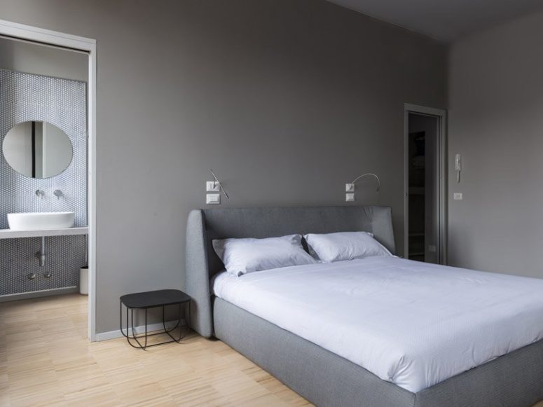 The bedroom is done in the shades of grey, with grey walls and a grey upholstered bed and a duo of metal bedside tables The bedroom is done in the shades of grey, with grey walls and a grey upholstered bed and a duo of metal bedside tables