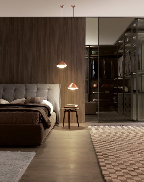 a masculine bedroom with a walk-in closet with a smoked glass wall partition to subtly divide the space