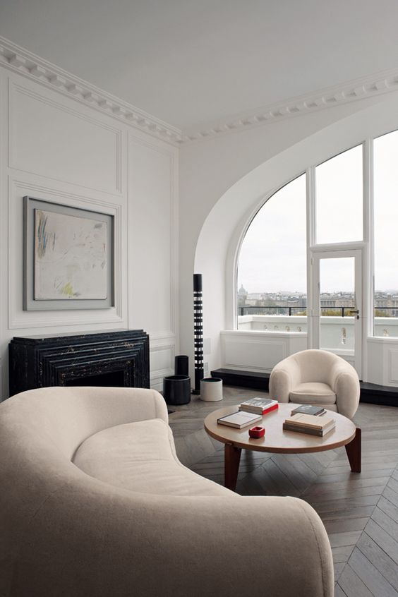 a refined and sophisticated living room with a curved sofa and chair in neutrals