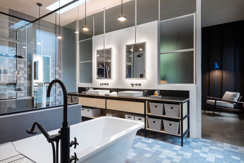The bathroom is a spacious room with much light, blue tones and many mirrors