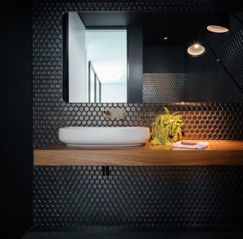 The bathroom is done with black hex tiles and a floating vanity