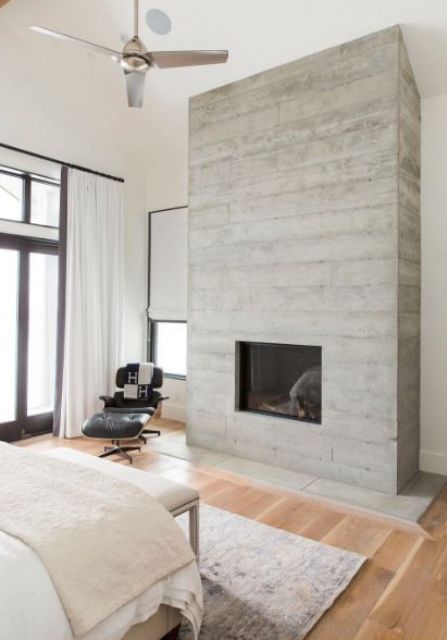 a neutral bedroom with touches of whitewahsed wood, with wooden floors and a leather chair plus various fabrics