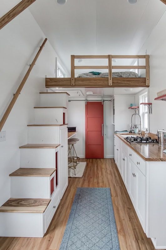 a sleeping space on the second level, a tiny dining space with a window sill and a sleek kitchen
